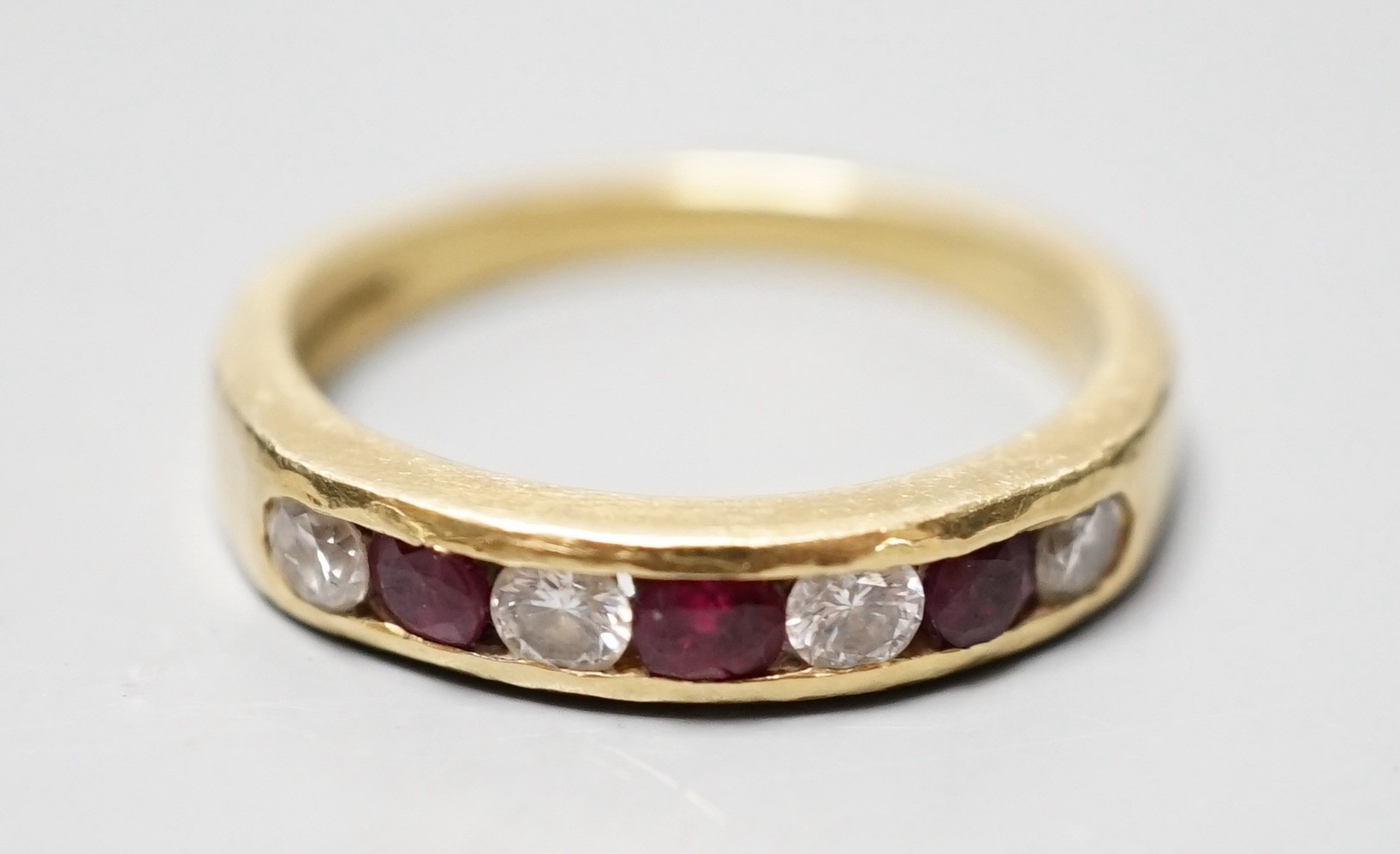 A modern 18ct gold and channel set four stone diamond and three stone ruby set half hoop ring, size N, gross weight 4.3 grams.